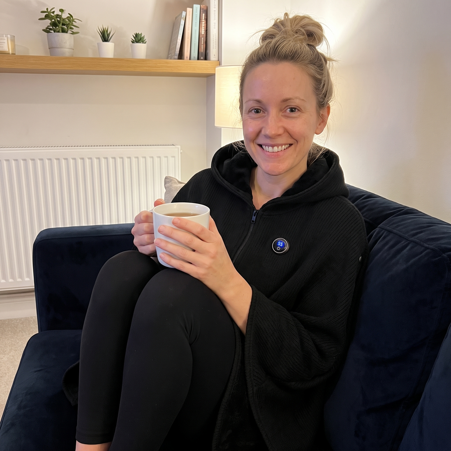 Woman on the sofa with tea wearing the heated poncho